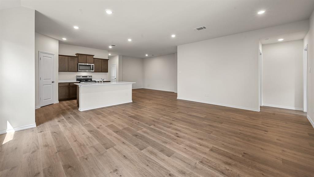 Open-concept living space featuring wood-finish flooring, recessed lighting, and a kitchen island with a sink
