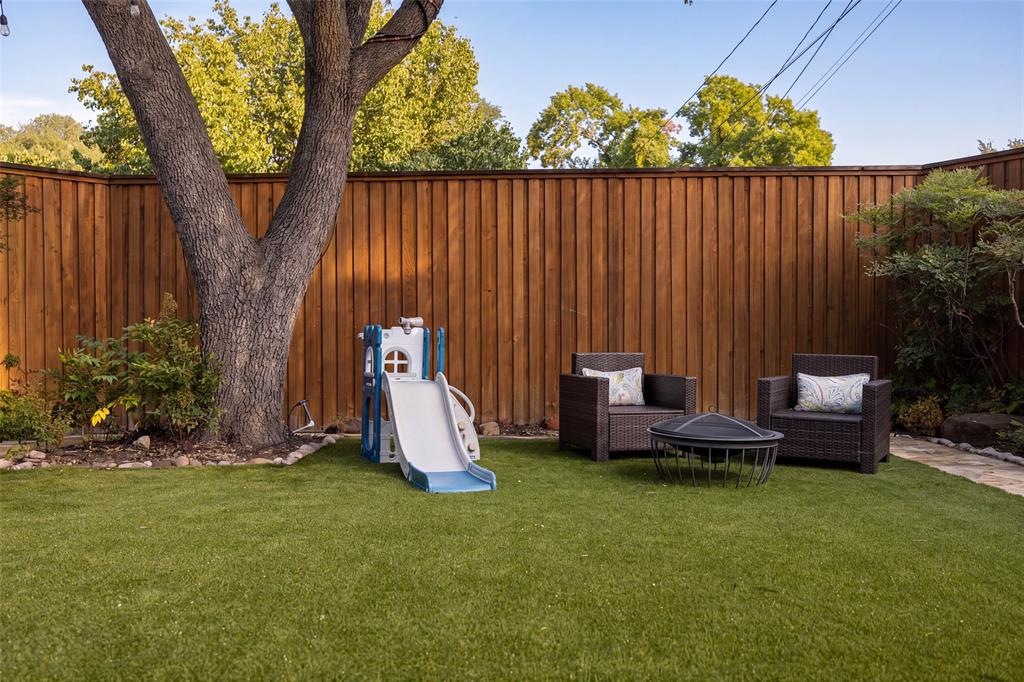 Private backyard featuring a full perimeter wood fence, mature tree, and artificial turf