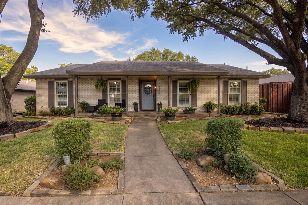 Brick exterior with dark shutters, covered front entry, and a concrete walkway