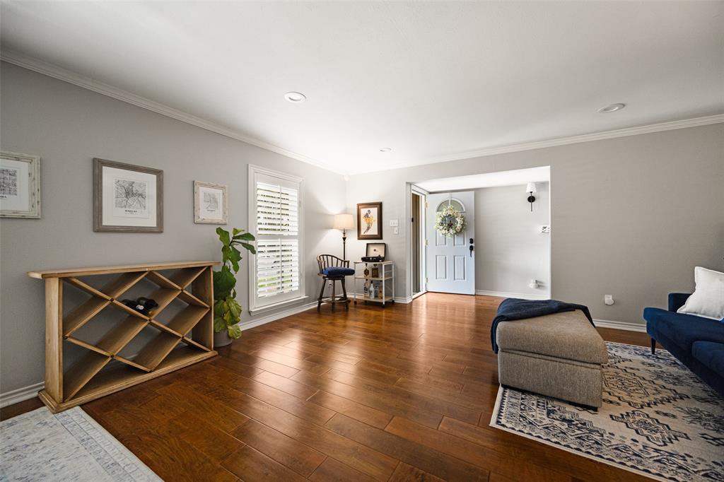 Hardwood-style flooring throughout, light gray wall paint, plantation shutters, recessed ceiling lighting, and a light blue entry door