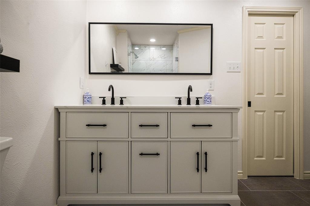 Dual vanity with white countertop, matte black fixtures, and cabinet storage
