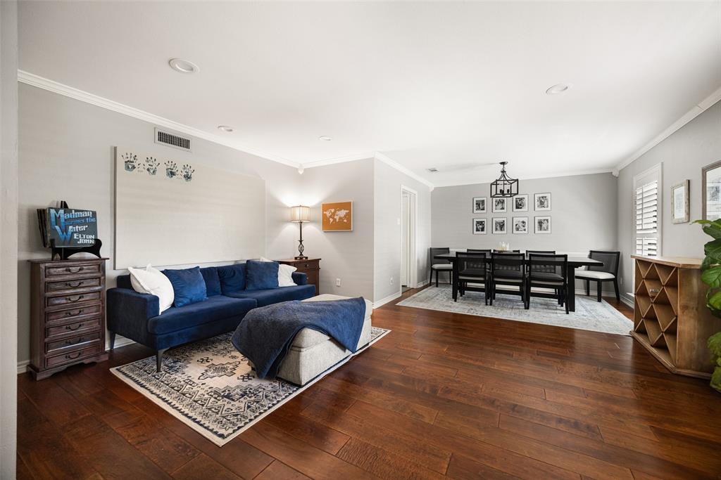 Wood-finish flooring throughout, featuring crown molding, recessed lighting, and a defined dining area with a chandelier