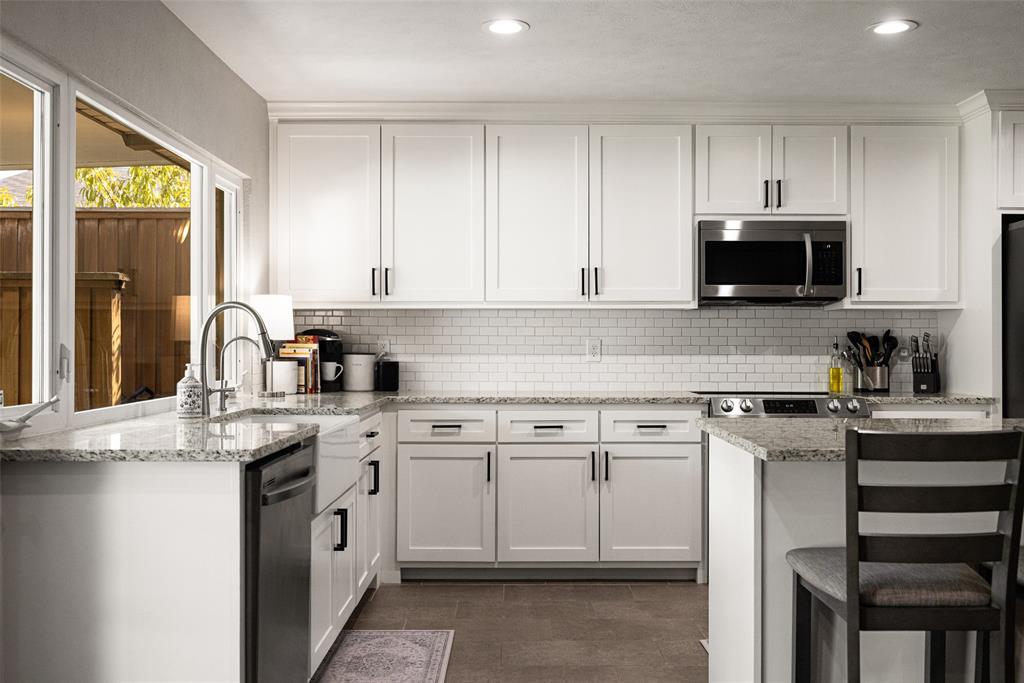 White shaker cabinetry, granite countertops, stainless steel appliances, subway tile backsplash, and recessed lighting