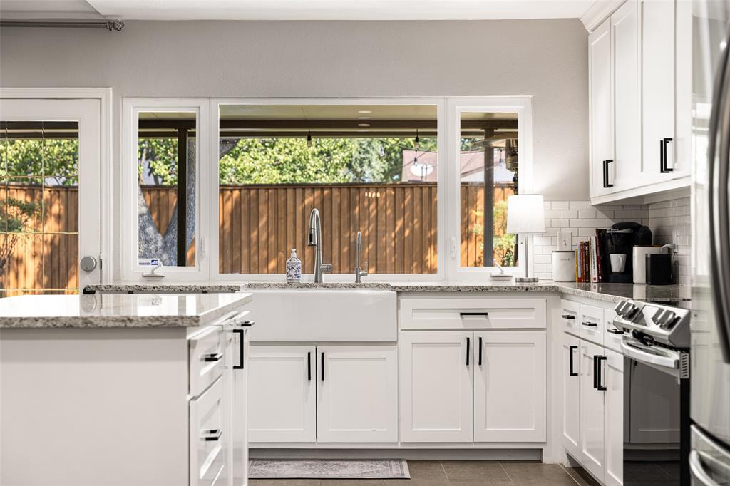 White shaker-style cabinetry with matte black hardware, stone-finish countertops, stainless steel appliances, and a farmhouse sink