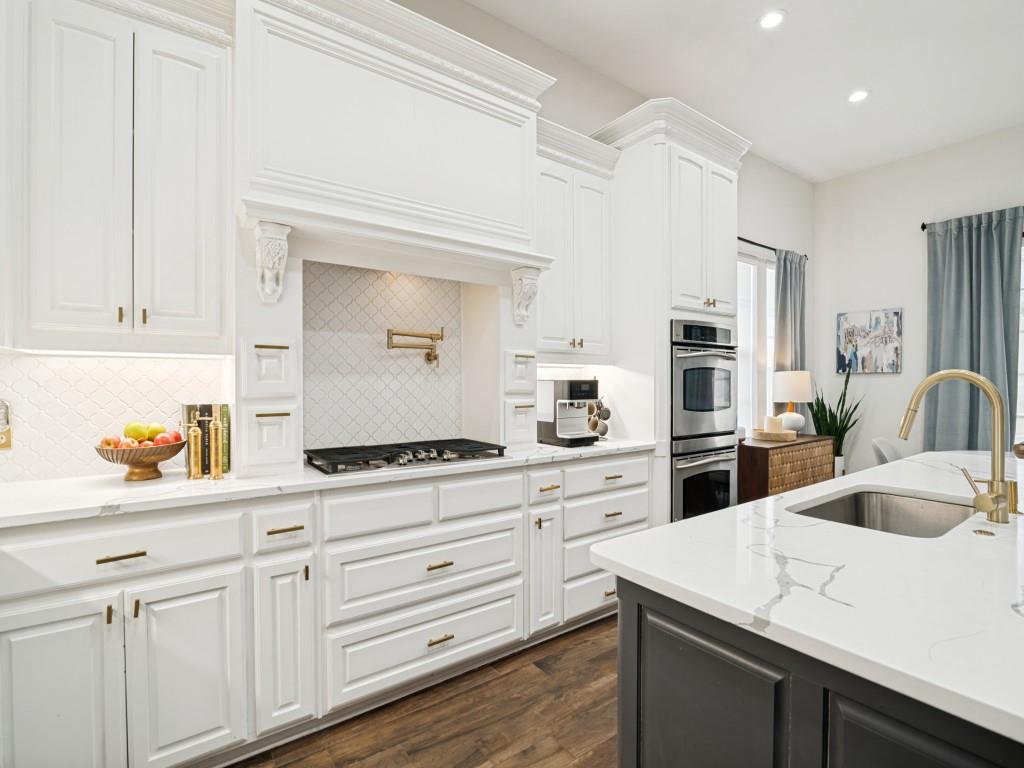 Gas cooktop, pot filler, and under-counter lighting in this bright kitchen.