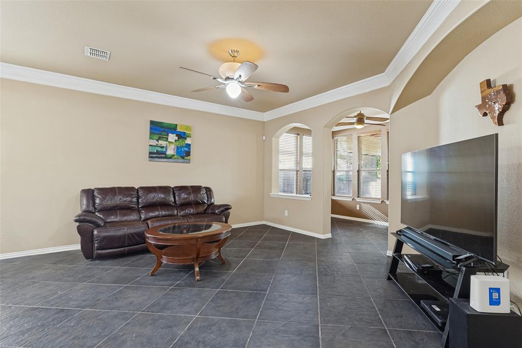 Tile flooring, crown molding, arched doorways, and ceiling fan.