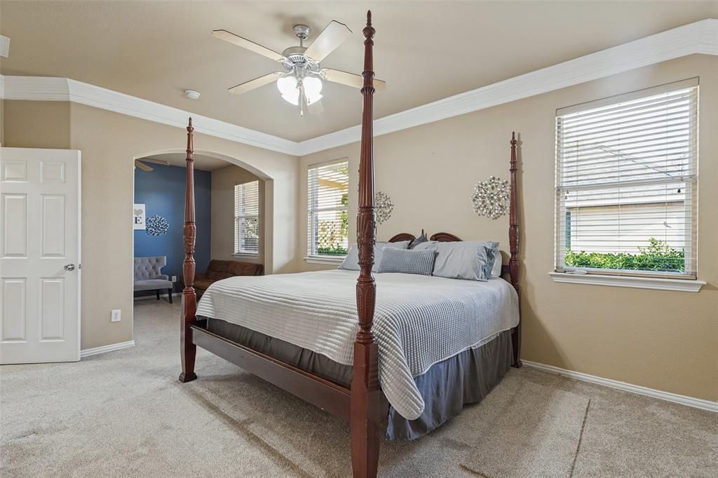 Neutral tone wall paint, crown molding, arched doorway, ceiling fan with integrated lighting, and carpeted flooring