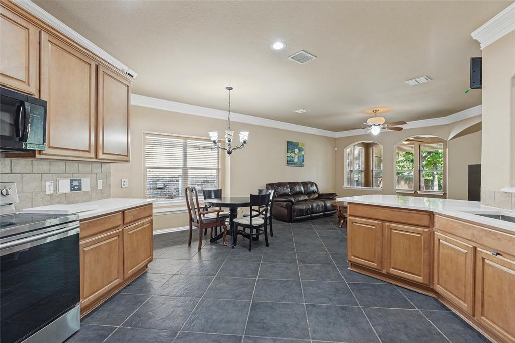 Kitchen with wood cabinetry, light countertops, and dark tile flooring