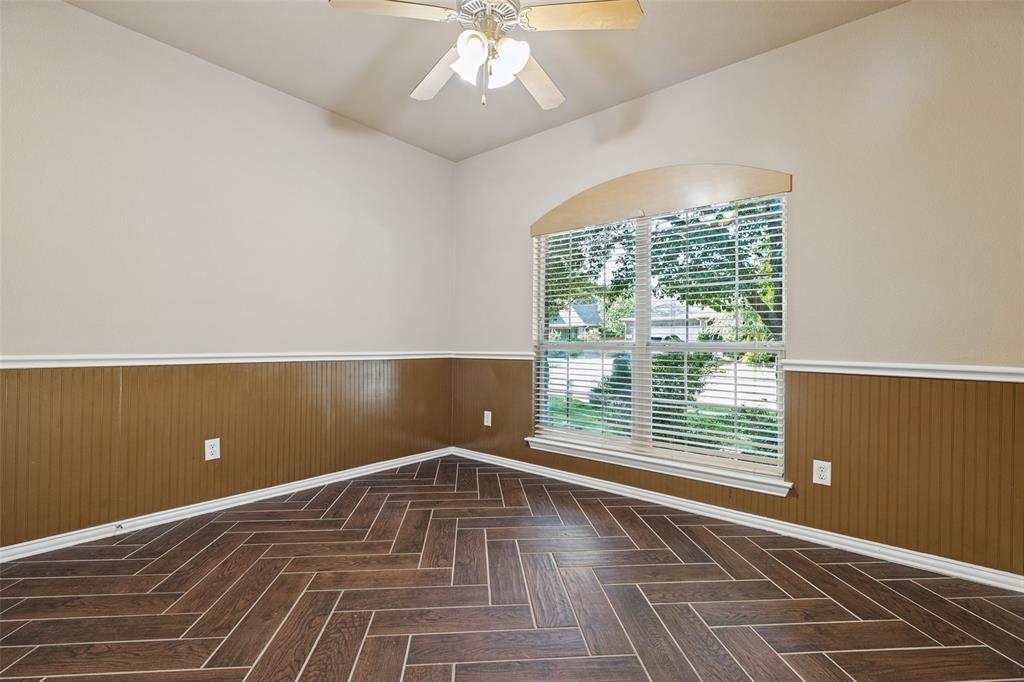 Wood look ceramic tile in a herringbone pattern, beadboard wainscoting, and a large window.