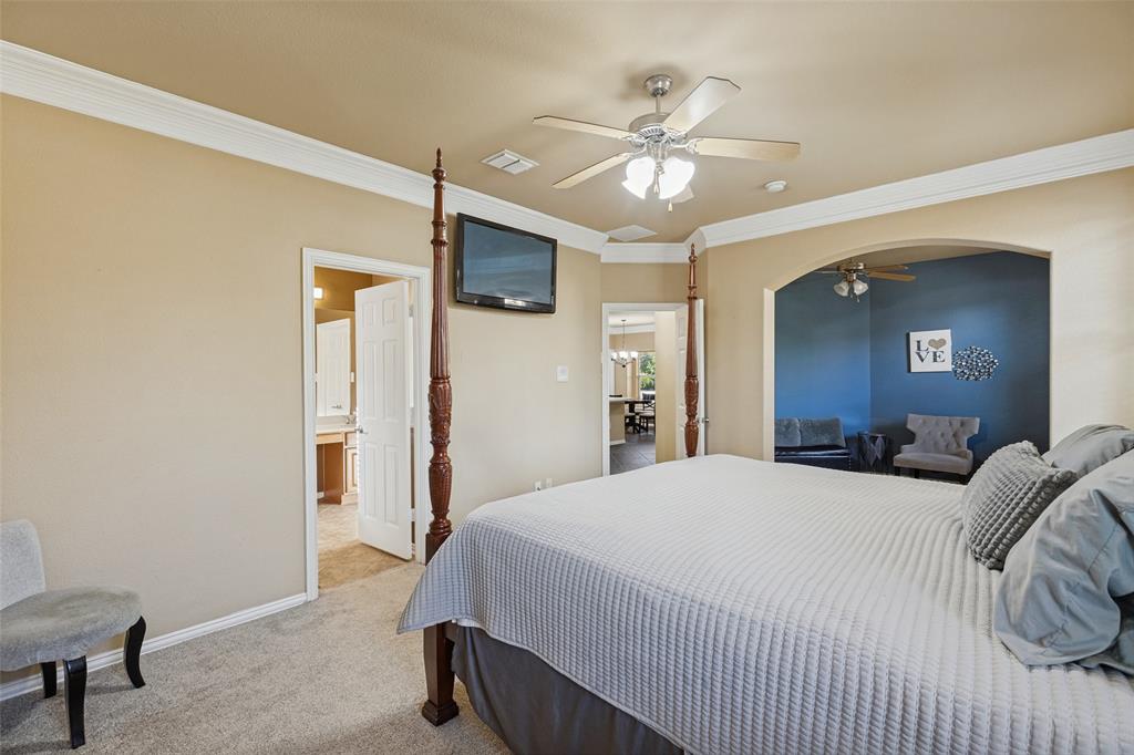 Carpeted room with a ceiling fan, crown molding, and an arched opening to bonus room