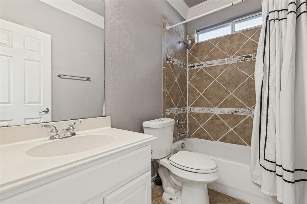 Bathroom featuring a white vanity, tiled shower surround with accent bands, and an upper window