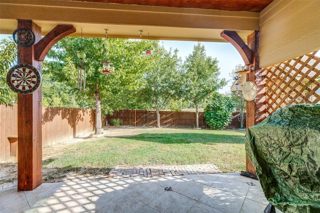 Custom covered patio featuring wood columns and a tiled floor, yard backs to greenbelt
