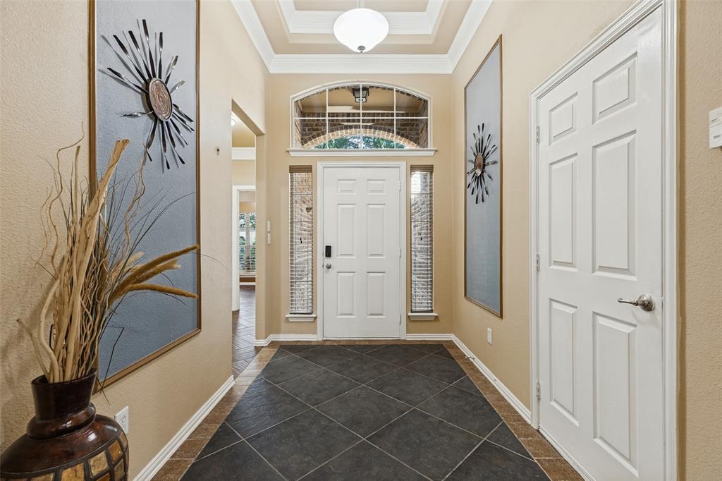 Entryway featuring dark diagonal tile flooring with a perimeter border, a coffered ceiling with a central light fixture, and an arched transom window above the entry door
