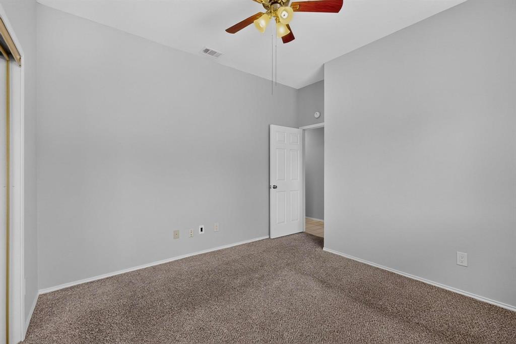Carpeted flooring with painted walls, a ceiling fan, and a white interior door