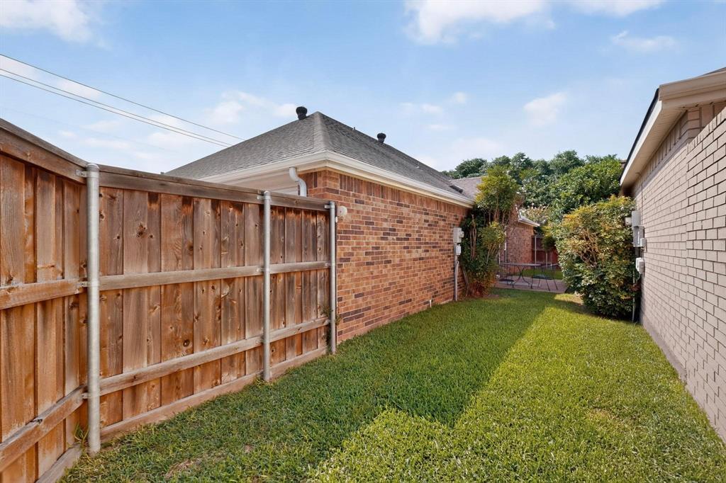 Fenced backyard featuring a wood fence, brick exterior, and a manicured lawn