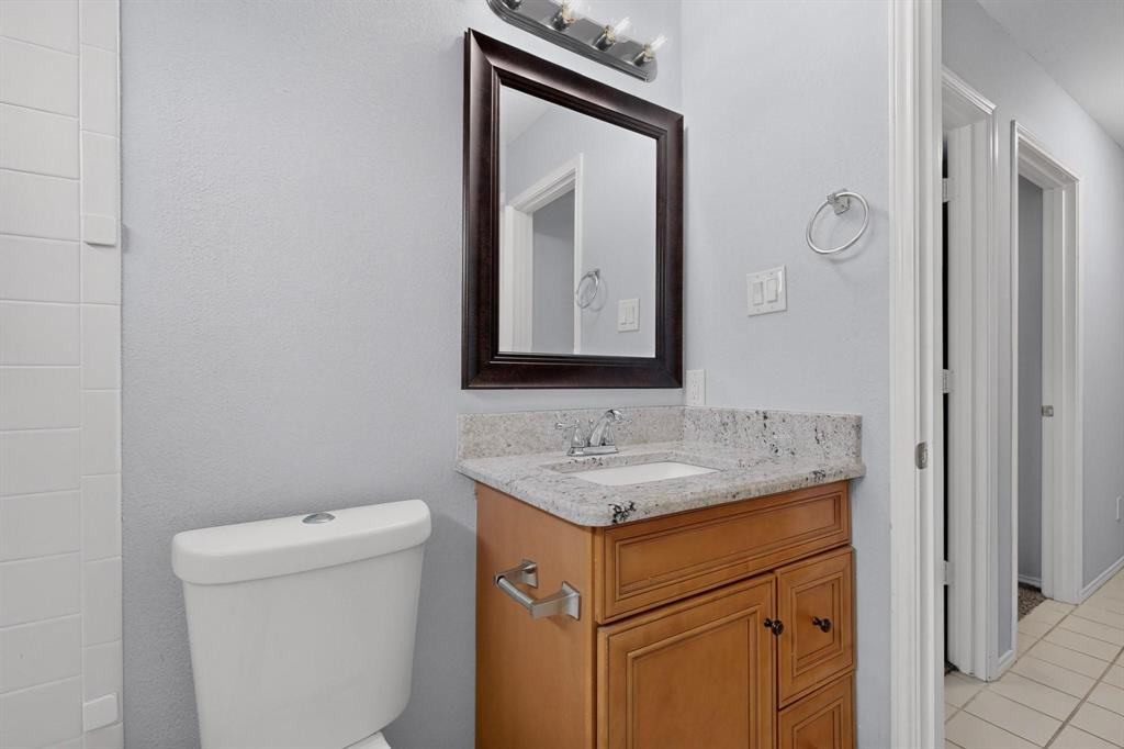 Vanity with light wood-finish cabinetry, integrated sink, and stone-finish countertop