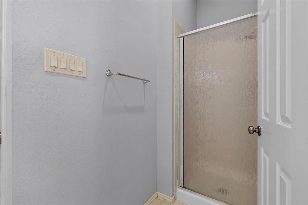 Enclosed shower with frosted glass door, light gray walls, and white trim