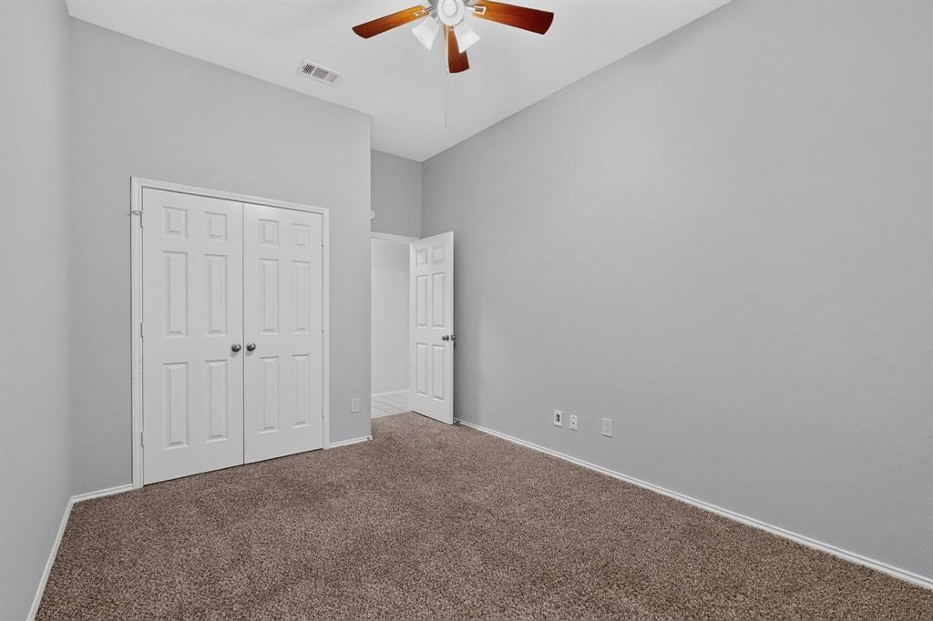Neutral gray wall finish, brown carpet, bi-fold closet doors, paddle ceiling fan, and white trim