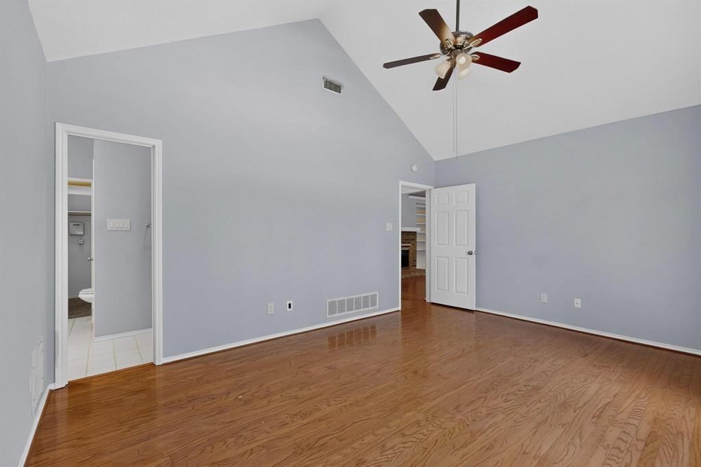 Vaulted ceiling with a ceiling fan, wood-finish flooring, and light-toned wall paint