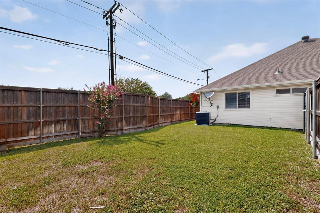 Expansive backyard with a manicured lawn, full wood privacy fence, and a blooming shrub