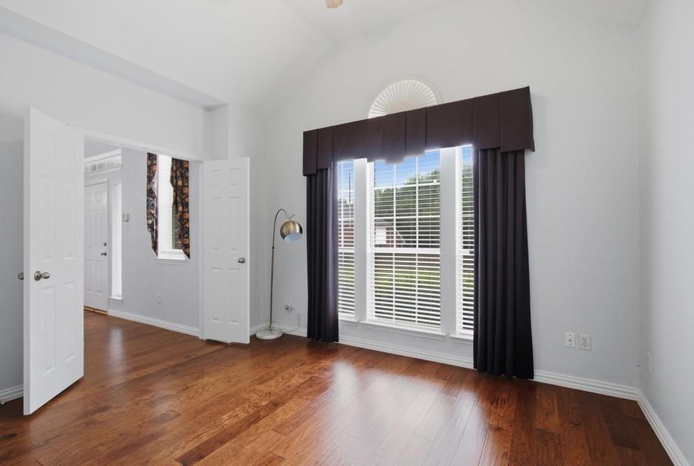 Vaulted ceiling, wood-finish flooring, broad window with louvered blinds, arched transom window, and double entry doors