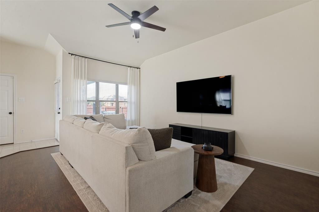 Vaulted ceilings, wood-finish flooring, ceiling fan, large window with blinds, and white interior paint Vaulted ceilings, wood-finish flooring, ceiling fan, large window with blinds, and white interior paint