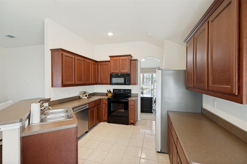 Kitchen featuring wood-finish cabinetry, stainless steel double-basin sink, stainless steel dishwasher, and a full suite of appliances Kitchen featuring wood-finish cabinetry, stainless steel double-basin sink, stainless steel dishwasher, and a full suite of appliances