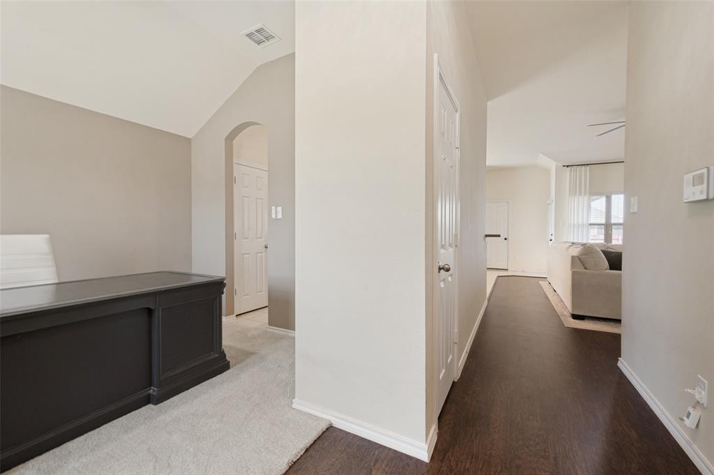 Vaulted ceiling with an arched entryway, dark wood-finish flooring, and light-colored walls Vaulted ceiling with an arched entryway, dark wood-finish flooring, and light-colored walls