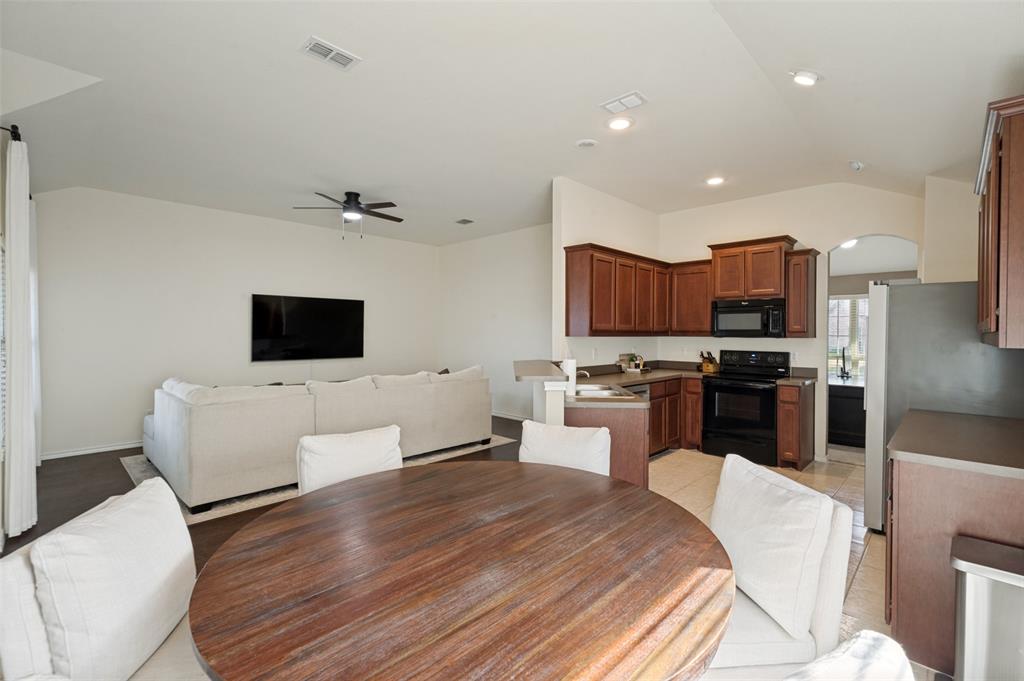 Kitchen with wood-finish cabinetry and black appliances, complemented by a breakfast bar Kitchen with wood-finish cabinetry and black appliances, complemented by a breakfast bar