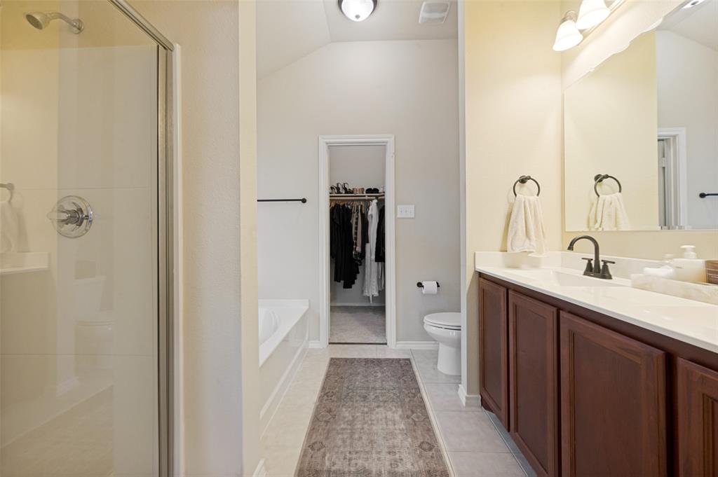 Bathroom featuring a glass-enclosed shower, built-in bathtub, dual-basin vanity with dark wood-finish cabinetry, and a walk-in closet