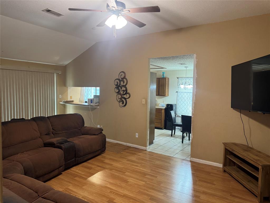 Vaulted ceilings with a ceiling fan, carpeted flooring, and window treatments