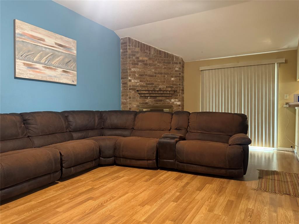 Vaulted ceiling with a ceiling fan, wood-finish flooring, and a pass-through window with a shelf