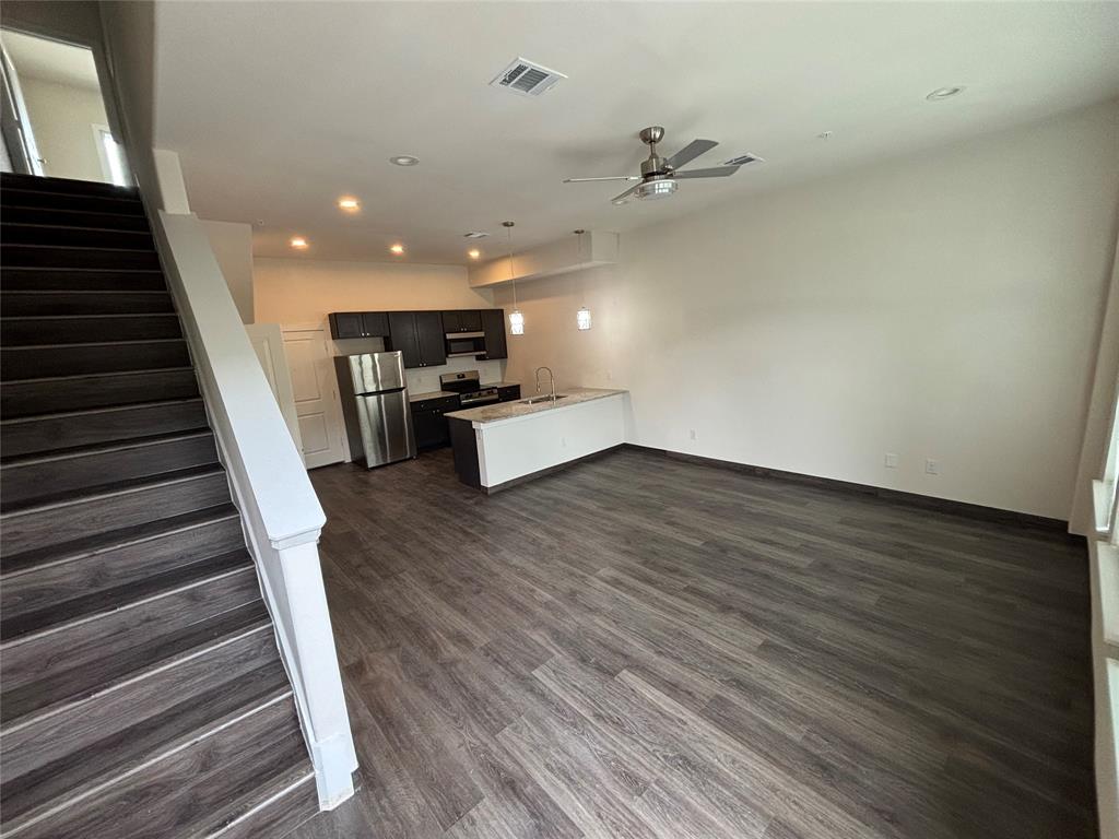 Open-concept living space with wood-finish flooring, recessed lighting, and a ceiling fan