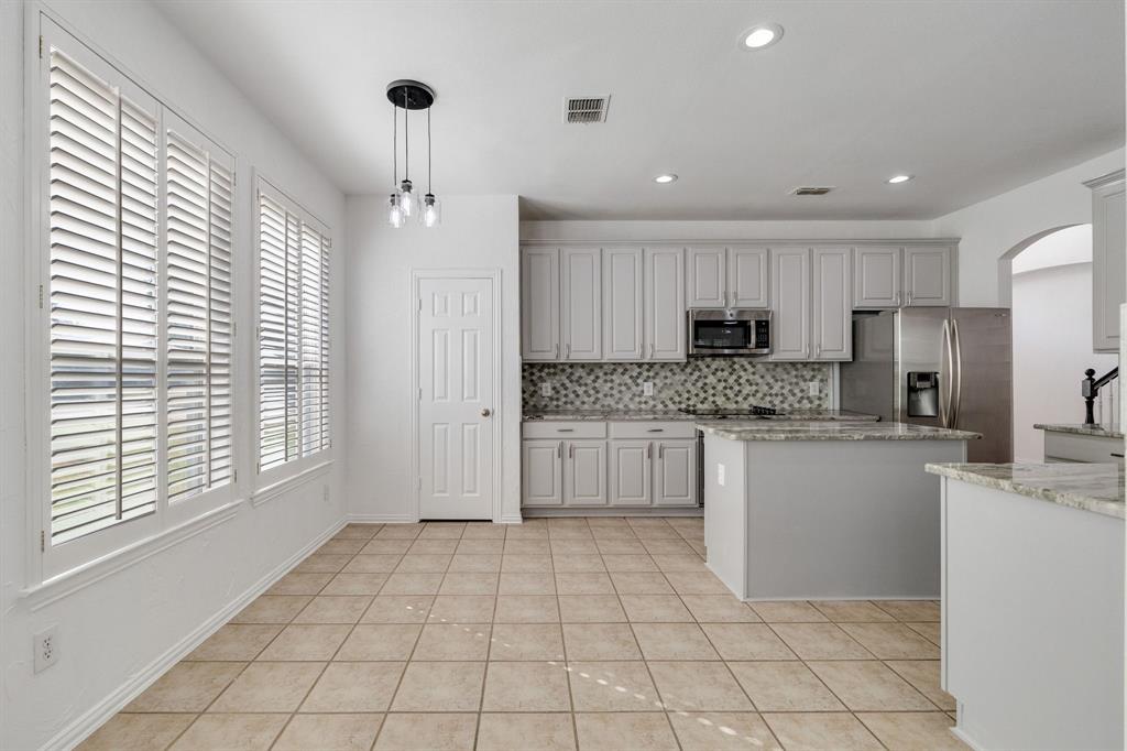 Kitchen featuring white cabinetry, stainless steel appliances, granite countertops, tile flooring, and a decorative tile backsplash