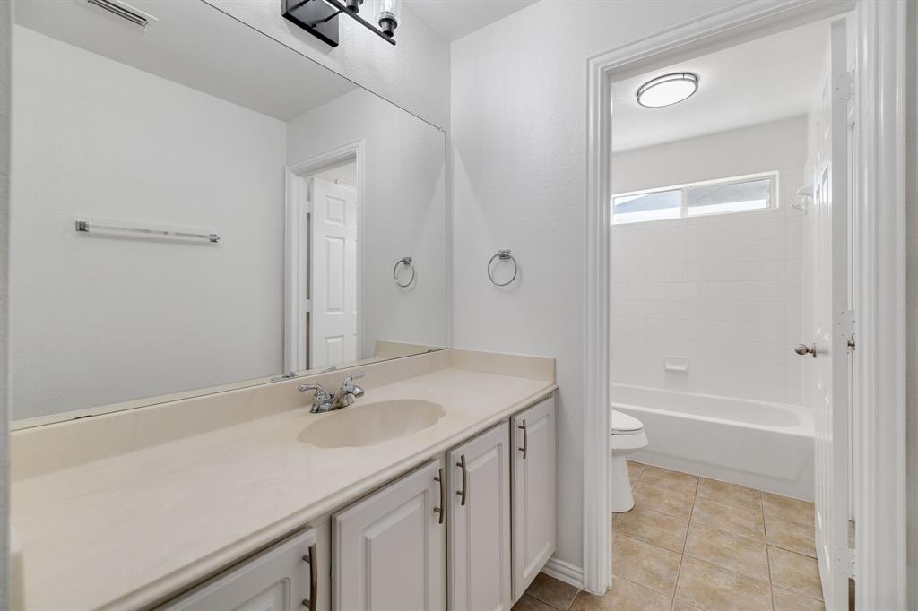 White paneled vanity with chrome hardware, an integrated sink, and an expansive wall mirror