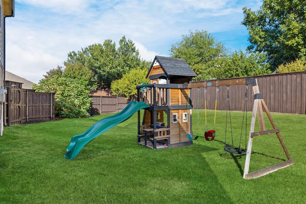 Expansive grassy lawn with a wood privacy fence and mature trees