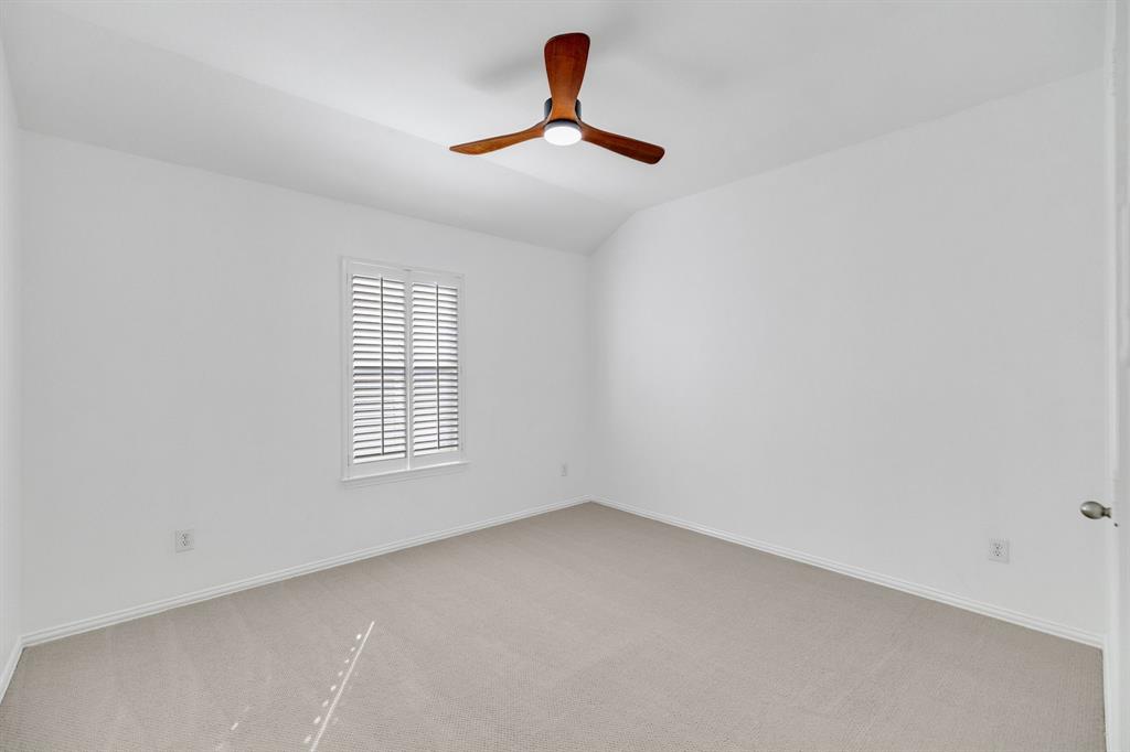 Carpeted flooring, white walls, window with plantation shutters, wood-finish ceiling fan with integrated lighting