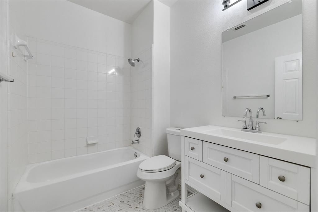 White vanity with integrated sink, chrome faucet, and rectangular mirror