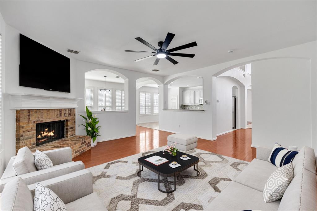 Brick fireplace with a substantial hearth, wood-finish flooring, recessed lighting, and arched architectural openings Brick fireplace with a substantial hearth, wood-finish flooring, recessed lighting, and arched architectural openings