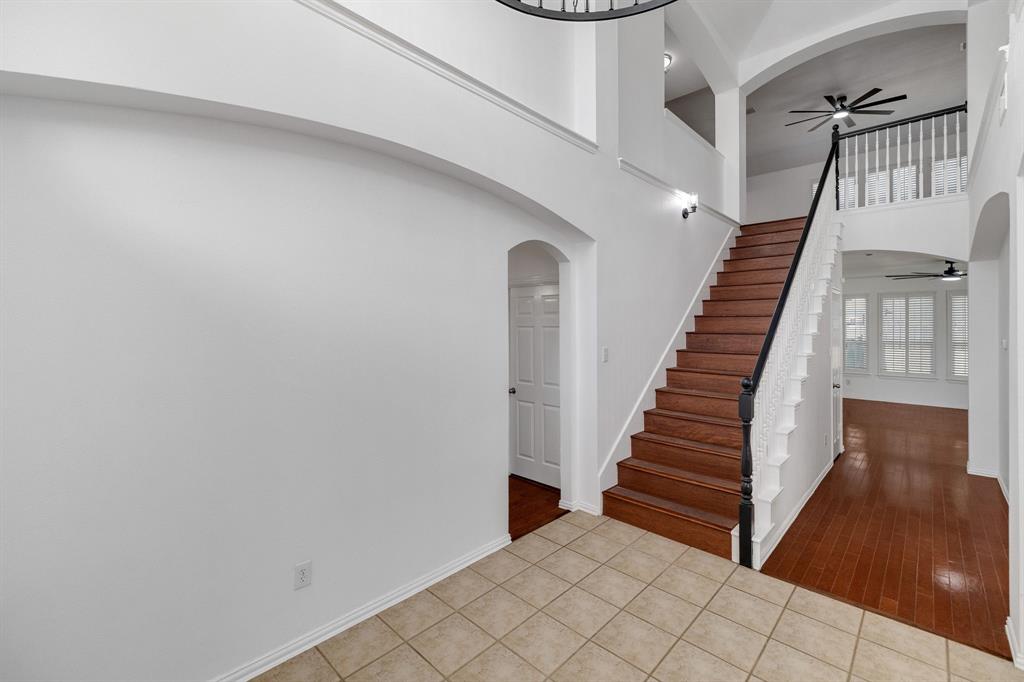 Tiled entry with wood-finish flooring, staircase with dark wood-finish handrail, and arched doorways Tiled entry with wood-finish flooring, staircase with dark wood-finish handrail, and arched doorways
