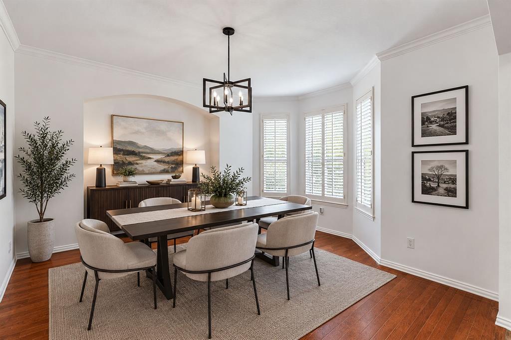 Hardwood flooring, arched wall niche, bay window with plantation shutters, crown molding, and a contemporary chandelier Hardwood flooring, arched wall niche, bay window with plantation shutters, crown molding, and a contemporary chandelier