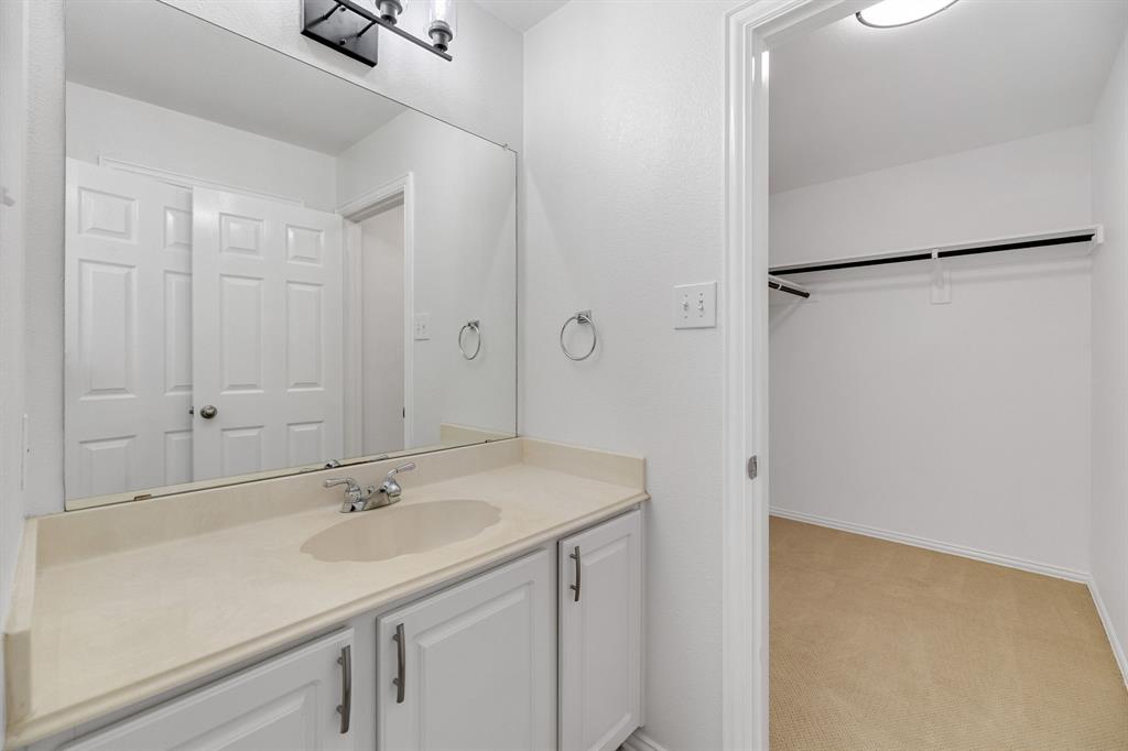 Vanity with integrated sink, chrome faucet, and white cabinetry