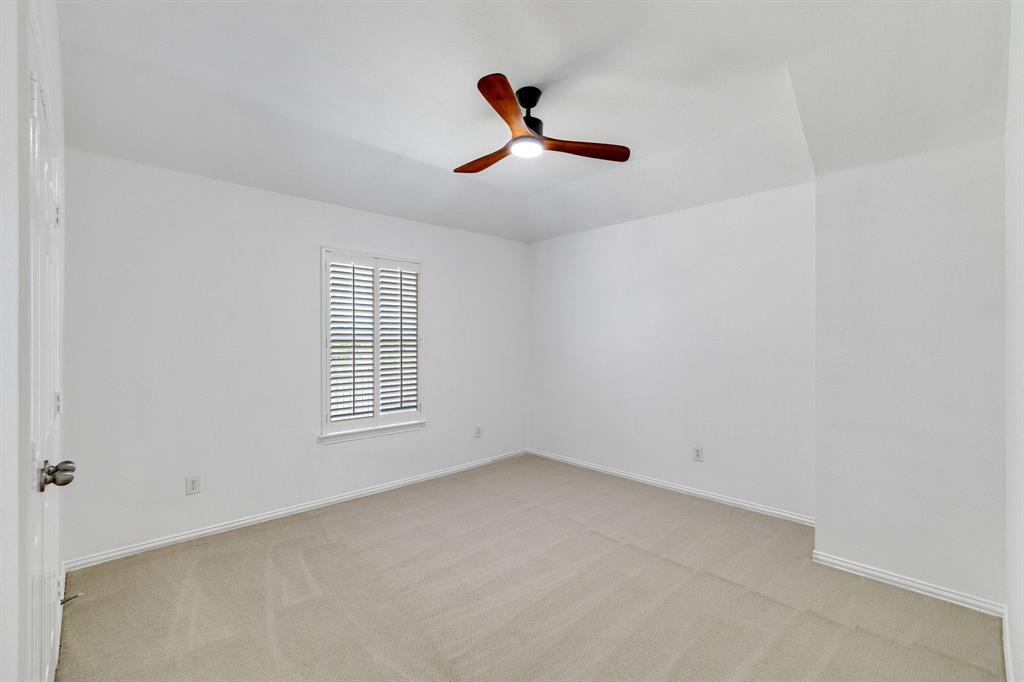Recessed window with plantation shutters, neutral carpeting, and a ceiling fan with integrated lighting