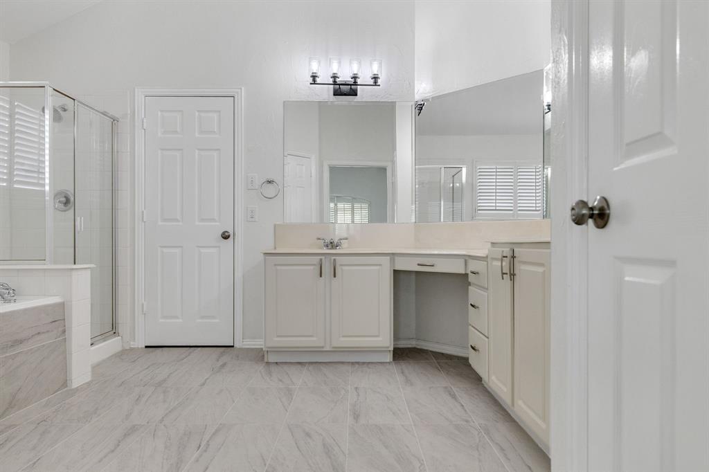 Dual vanity with integrated sink, glass-enclosed shower, built-in bathtub with tiled surround, wood-finish flooring, and vanity lighting