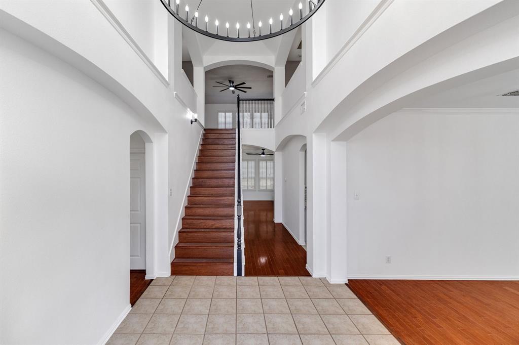 Two-story entryway with a decorative chandelier, a wood staircase, and an arched entry Two-story entryway with a decorative chandelier, a wood staircase, and an arched entry