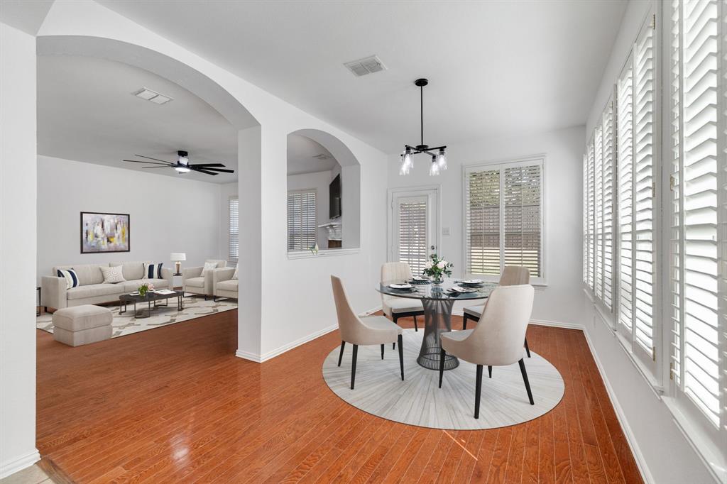 Arched doorways, wood-finish flooring, white plantation shutters, built-in ceiling fan, and a modern chandelier Arched doorways, wood-finish flooring, white plantation shutters, built-in ceiling fan, and a modern chandelier