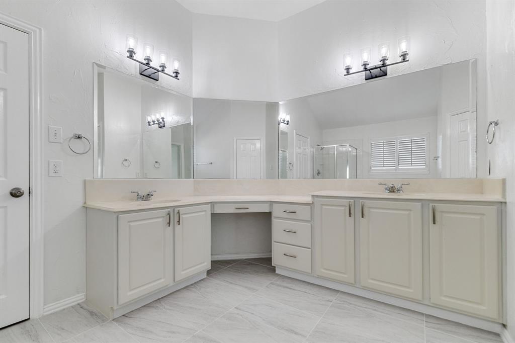 Dual vanity with light-toned countertops, white cabinetry, expansive mirrors, and decorative light fixtures
