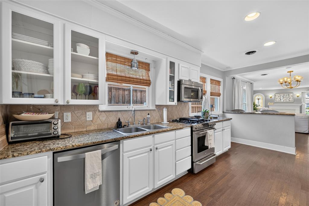 White cabinetry with glass-front uppers, stainless steel appliances, granite countertops, and wood-finish flooring
