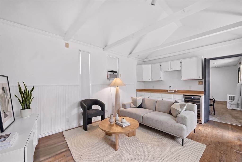 Vaulted beamed ceiling over a kitchenette with white cabinetry, wood-finish countertops, and a built-in beverage refrigerator