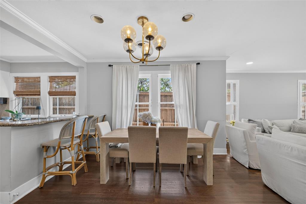 Recessed lighting, wood-finish flooring, gold-finish chandelier, crown molding, and a granite-finish breakfast bar